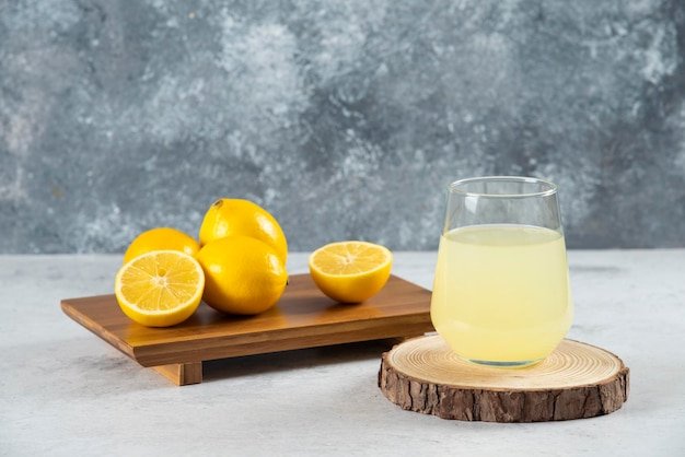 A glass cup of fresh lemon juice on a wooden board.