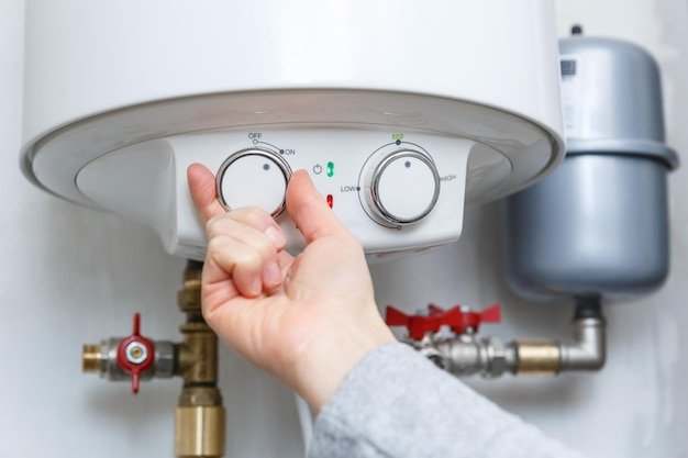 Female hand turning on electric water heater (boiler). household enegry saving equipment