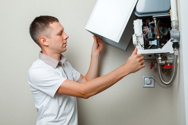 Plumber attaches trying to fix the problem with the residential heating equipment. repair of a gas boiler